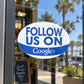 Oval white vinyl sticker with blue “FOLLOW US ON” text and “Google+” below