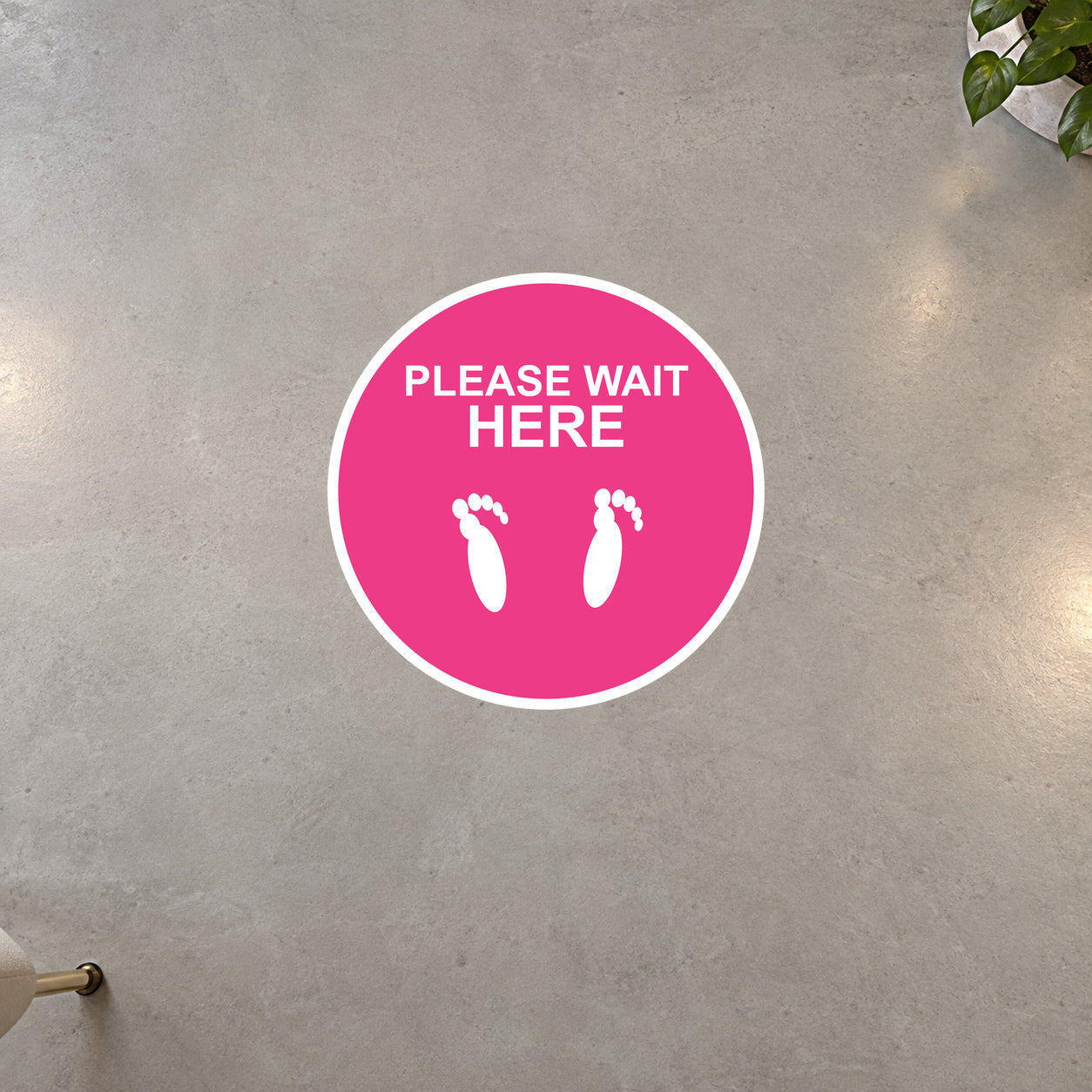 Pink circular “PLEASE WAIT HERE” non-slip floor sticker with white foot icons