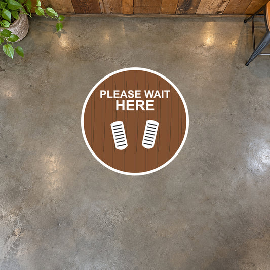 Non-slip circular floor sticker reading "PLEASE WAIT HERE" with boot-print icons