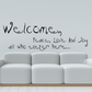 Wall decal with black script text: Welcome, Peace Love and Joy, all who enter here