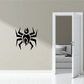 Black abstract spider decal with stylized body and legs on a light wall