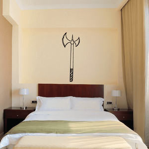 Axe wall decal with black handle and gold blade, centered above bed