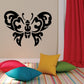 Black butterfly wall decal with ornate symmetrical wings on a light wall
