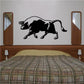 Black bull charging decal with long horns and curved tail on wall