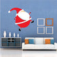 Santa tiptoe wall sticker with red suit and white beard, carrying a small sack.