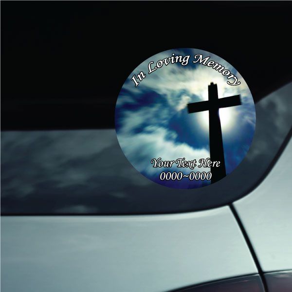 Round memorial sticker with black cross, blue sky clouds, and custom loving memory text