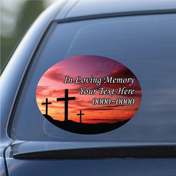 Oval memorial sticker with sunset, black crosses, and 'In Loving Memory'.