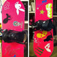 Pink snowboard with multicolor vinyl decal graphics, including cartoon-style icons