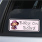 Baby on Board sticker with cartoon baby girl in hat holding doll