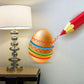 Decorated Easter egg with orange shell and colorful zigzag striped bands