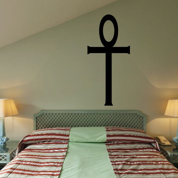 Black Egyptian ankh decal with simple looped cross, centered on a wall above a bed