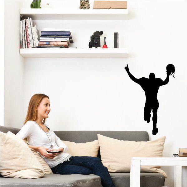 Black football player wall decal silhouette with one arm raised and ball near foot