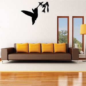 Black hummingbird wall decal with wings spread, feeding on flowers