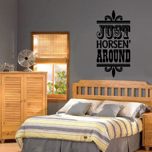 Black vinyl wall quote decal with text "Just Horsen Around" above bed
