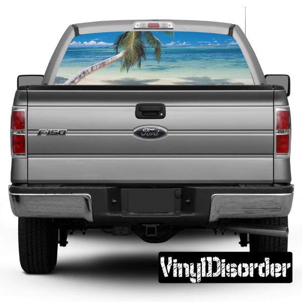 Gray pickup truck rear window graphic with palm beach scene, tailgate and bumper visible.