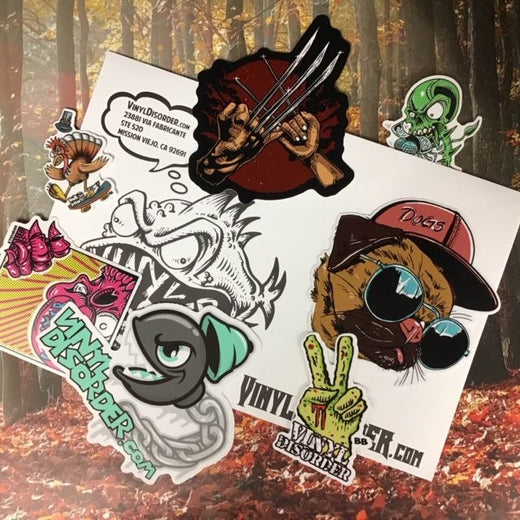 Monthly sticker pack sheet with assorted cartoon vinyl stickers in dark, green, and pink