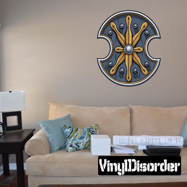 Circular shield sticker with notched metal rim, dark blue interior, gold axes and rivet details