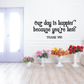 Curly wall decal with black script: “Our day is happier because you’re here” + “THANK YOU”