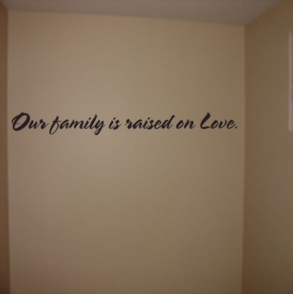 Wall decal with cursive quote: “Our family is raised on Love.”