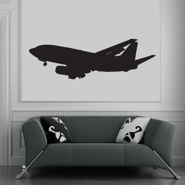 Black passenger jet landing decal silhouette on wall above sofa