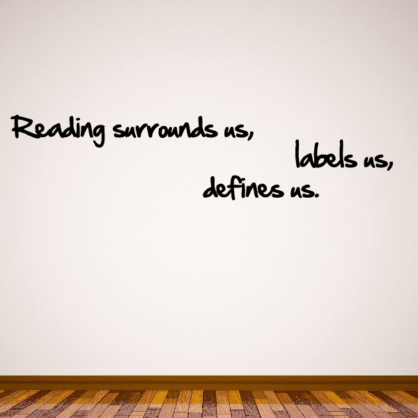 Wall decal with black cursive quote: 'Reading surrounds us, labels us, defines us.'