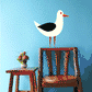 Seagull sticker of a white bird with black wing, orange beak, and red legs