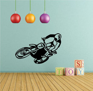Black dirt bike decal of rider doing slide turn, mounted on a panel surface