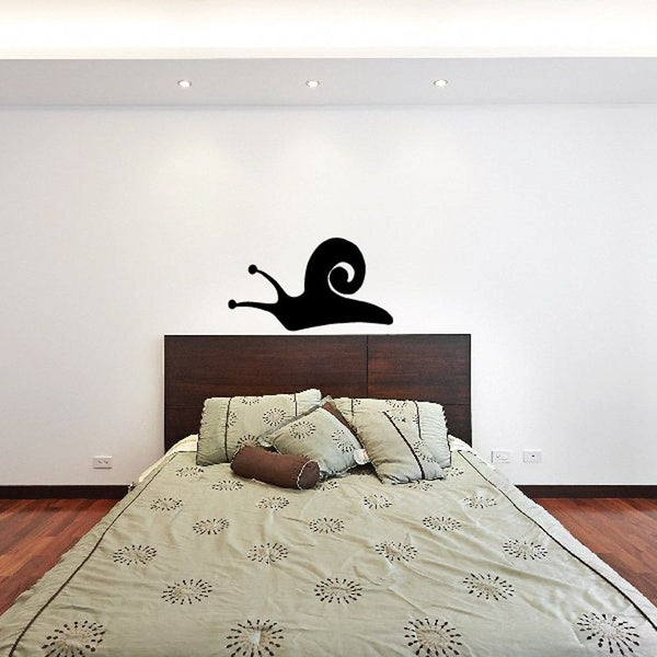 Black swirl snail wall decal with shell spiral silhouette above bed