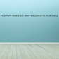 Wall decal with 'Sit down and feed, and welcome to our table' lettering