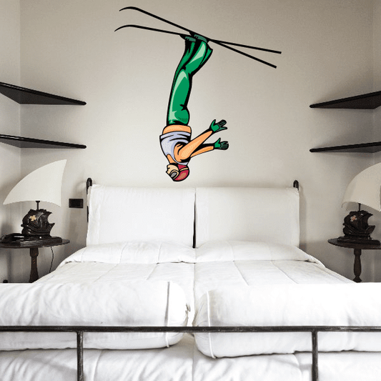 Skiing wall decal sticker of an airborne skier with teal skis and orange suit.