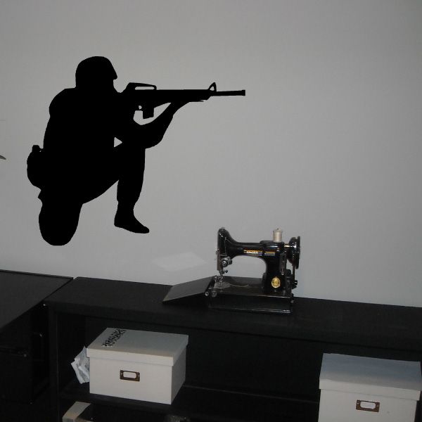 Soldier aiming decal, dark silhouette holding rifle on light background