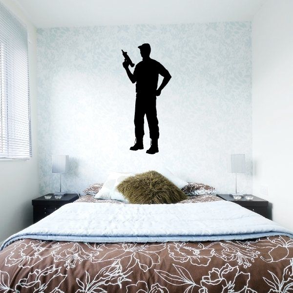 Wall decal of soldier holding an Uzi, black silhouette above a bed