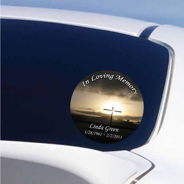 Circular memorial sticker with 'In Loving Memory' text and a cross at sunset