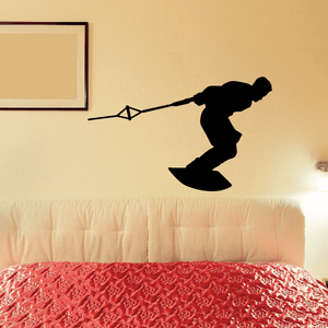 Black wakeboarding decal of a surfer holding rope, mid-air over a wakeboard.