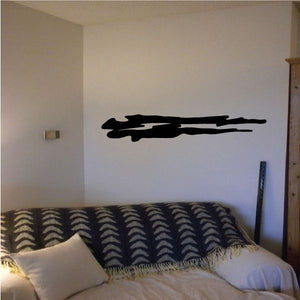 Tribal pinstripe wall decal, black elongated symbol on wall above a bed