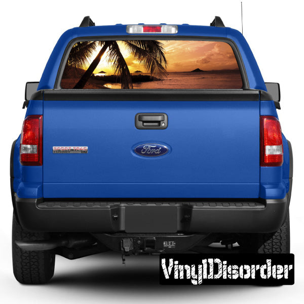 Vehicle rear window graphic with tropical palm and sunset scene, on blue pickup