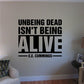 Black typography wall decal reading “UNBEING DEAD ISN’T BEING ALIVE” by E.E. Cummings