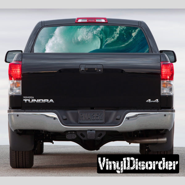 Waves rear window view graphic on dark pickup tailgate with centered badge area