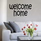 Welcome home wall decal with black cursive lettering on white wall