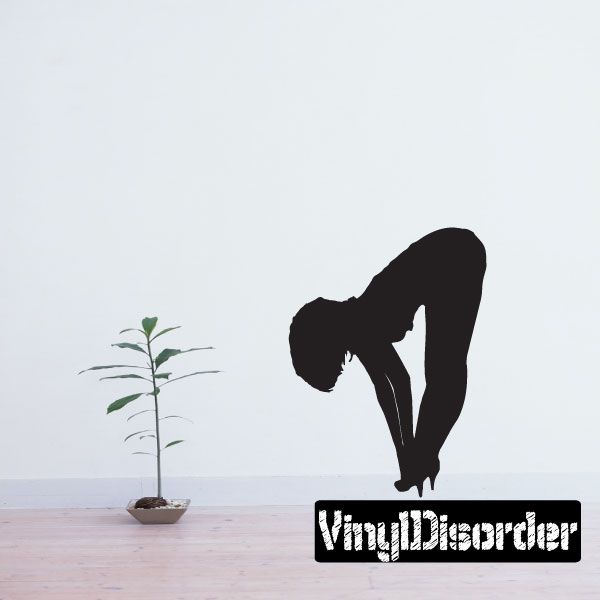 Black silhouette wall decal of a woman fixing her heels