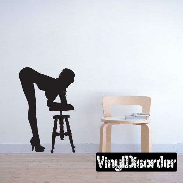 Black silhouette wall decal of a woman leaning over a stool.