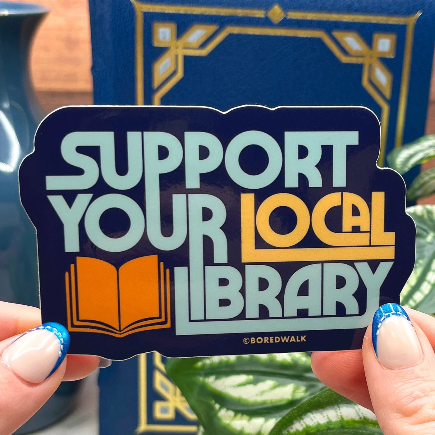 Boredwalk's Support Your Local Library Die Cut Sticker photographed as a finished sticker