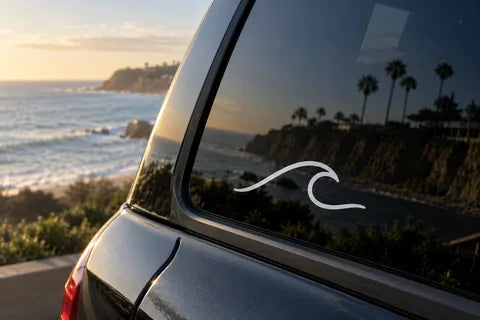 Coastal application example: a white wave decal on dark glass with the surface visible around the vinyl
