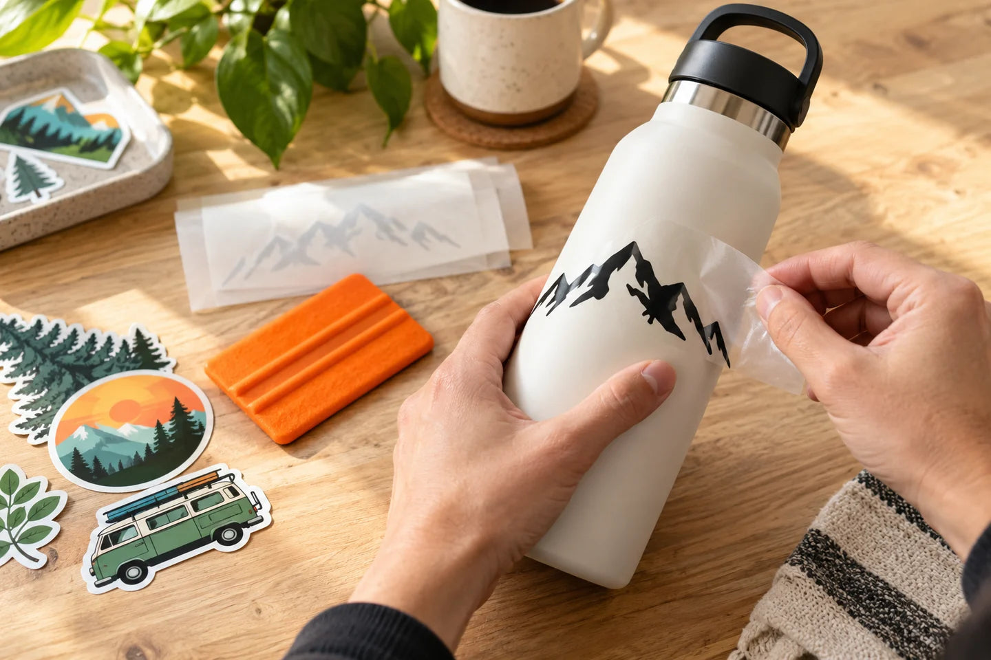 Hands applying a mountain decal to a bottle — illustrative creative scene