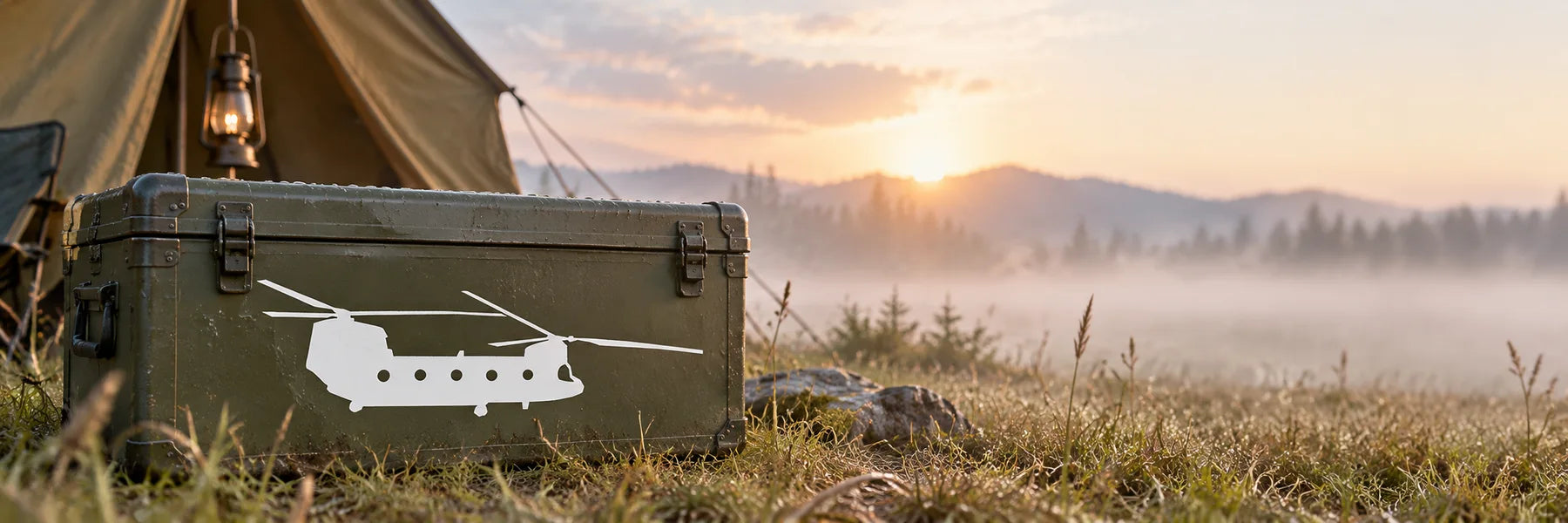 Illustrative Military Helicopter Decals application scene: Olive-green expedition storage trunk at an outdoor aviation campsite, exact reference CH-47 twin-rotor helicopter silhouette as WHITE cut vinyl, canvas tent and wild grass, misty early morning. No ammunition or invented military markings.