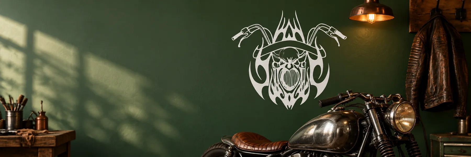 Illustrative Motorcycle Plaque Decals application scene: A genuine rider’s workshop wall, smooth painted deep forest green carrying the exact reference skull/handlebar graphic in white vinyl, vintage motorcycle, hanging leather jacket and warm copper light. Spacious room scene, no vehicle window or gear case.