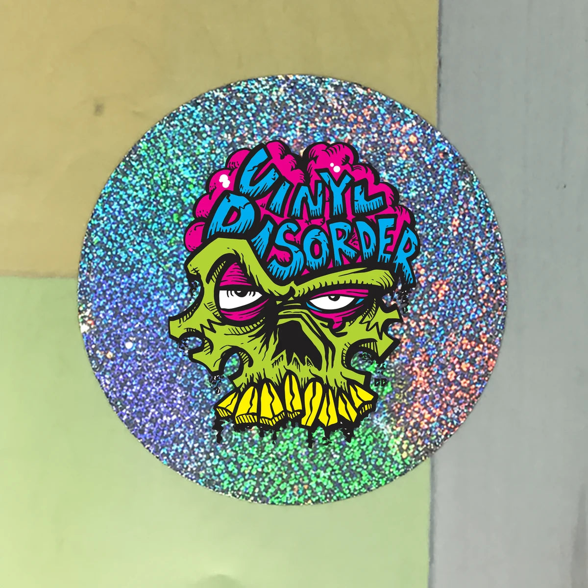 Glitter chrome circular sample with authentic Vinyl Disorder skull artwork and exposed sparkling border.