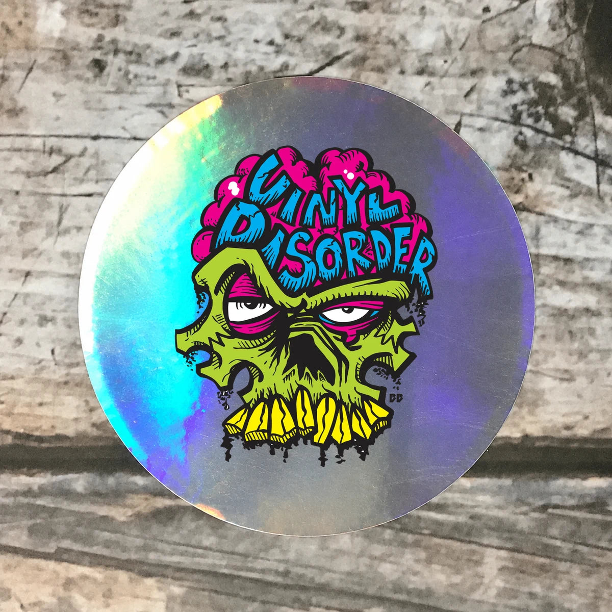 Oil slick rainbow chrome circular sample with authentic Vinyl Disorder skull artwork and exposed reflective border.